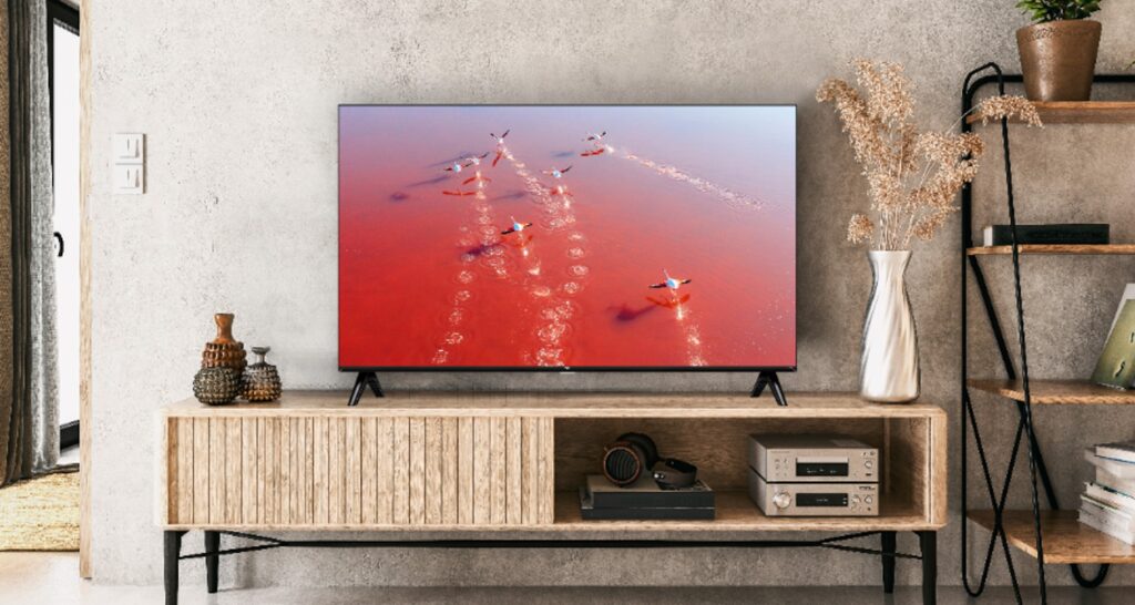 Televisor moderno mostrando aviones sobre un fondo rojo en un salón decorado.